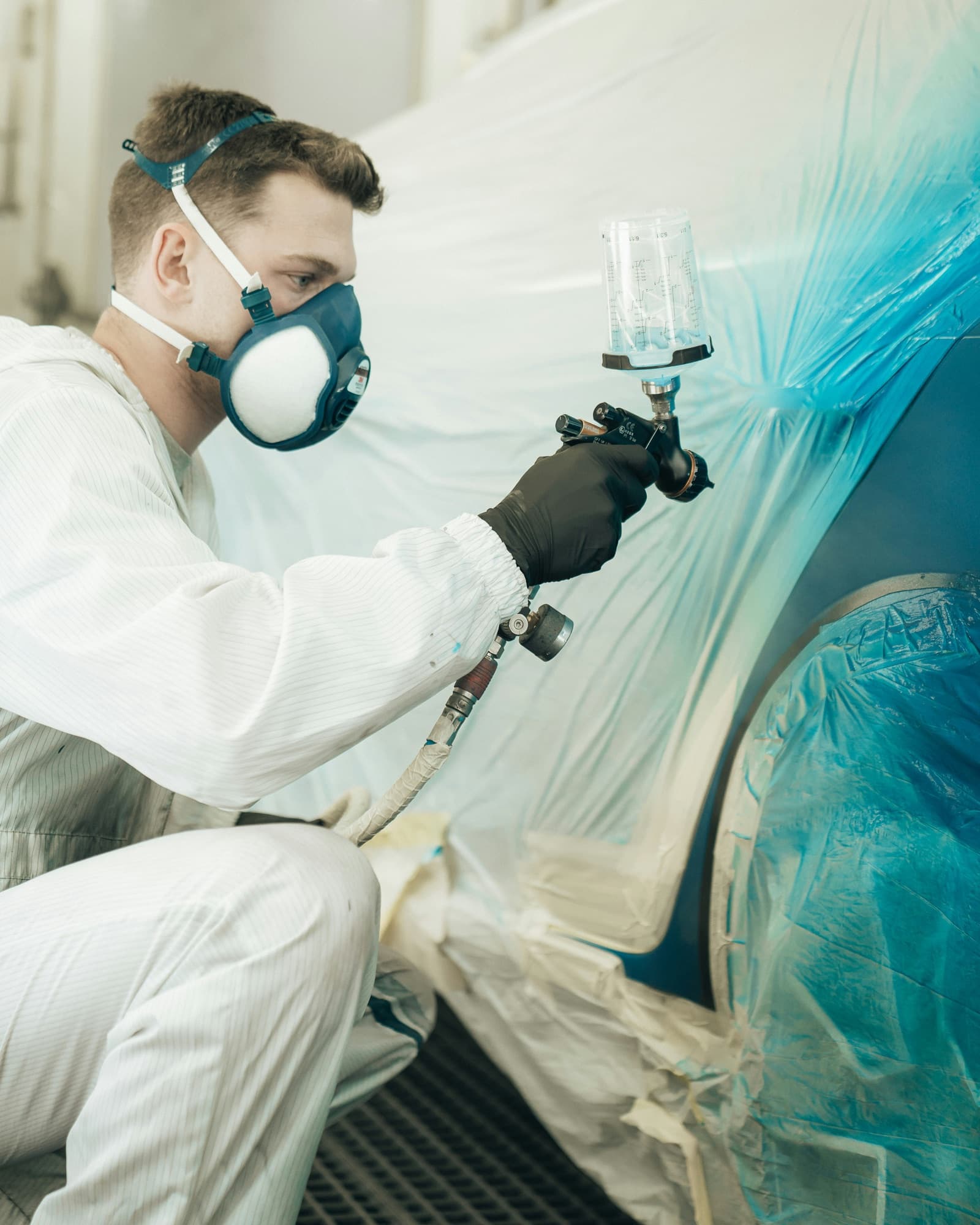 Aplicación de pintura automotriz con pistola en cabina